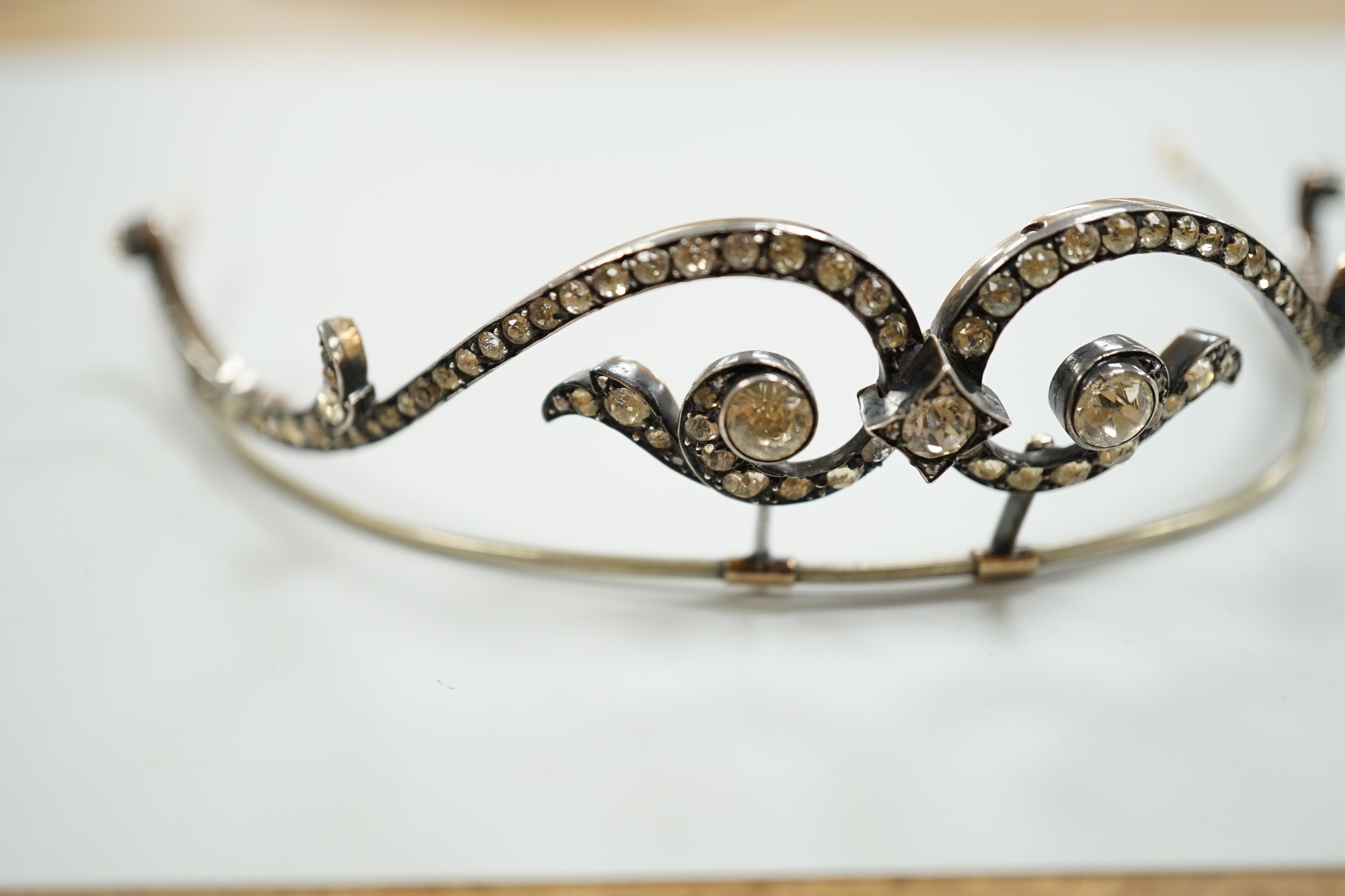 A 19th century, white and yellow metal paste cluster set tiara, width 13cm, the central stone with rose cut diamond chip spacers.